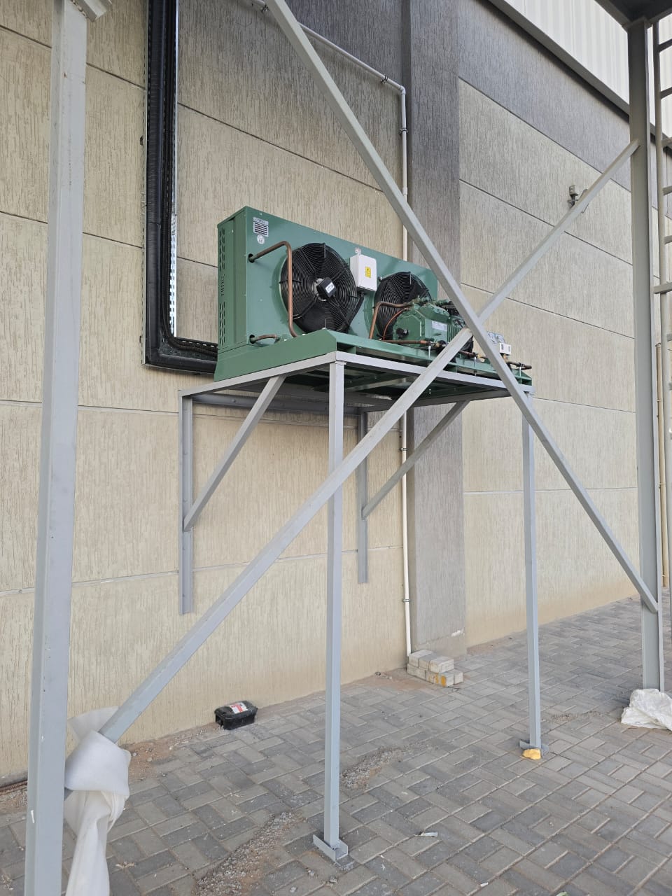 Air-cooled condensing unit installed on a fabricated steel support frame at a Dubai cold store facility