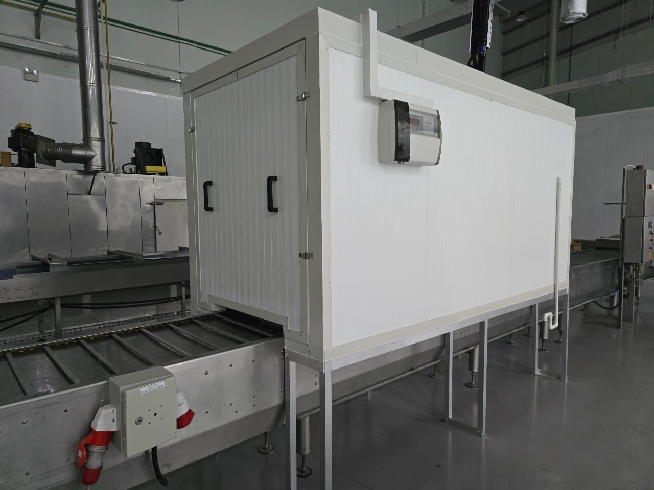 Panel-built cooling tunnel with externally mounted digital temperature controller over a food processing conveyor