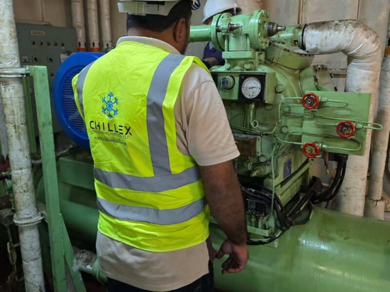 Chillex technicians in branded PPE servicing a reciprocating provision plant compressor in a vessel machinery space