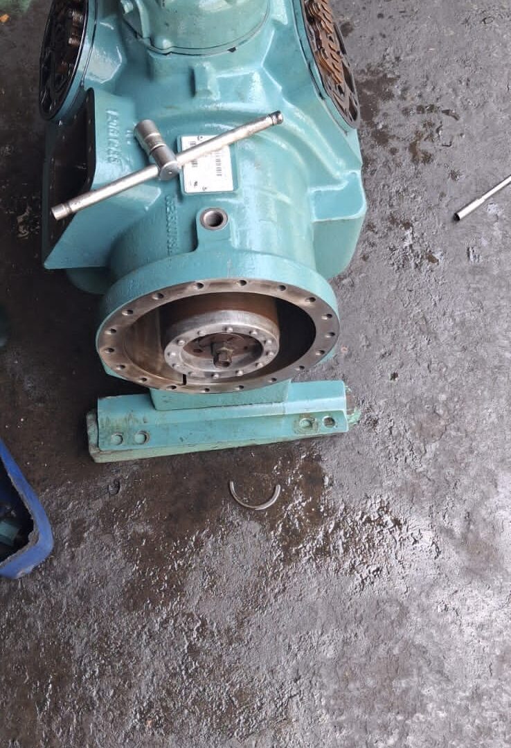 Refrigeration compressor stripped down on the workshop floor with valve plates exposed at both ends